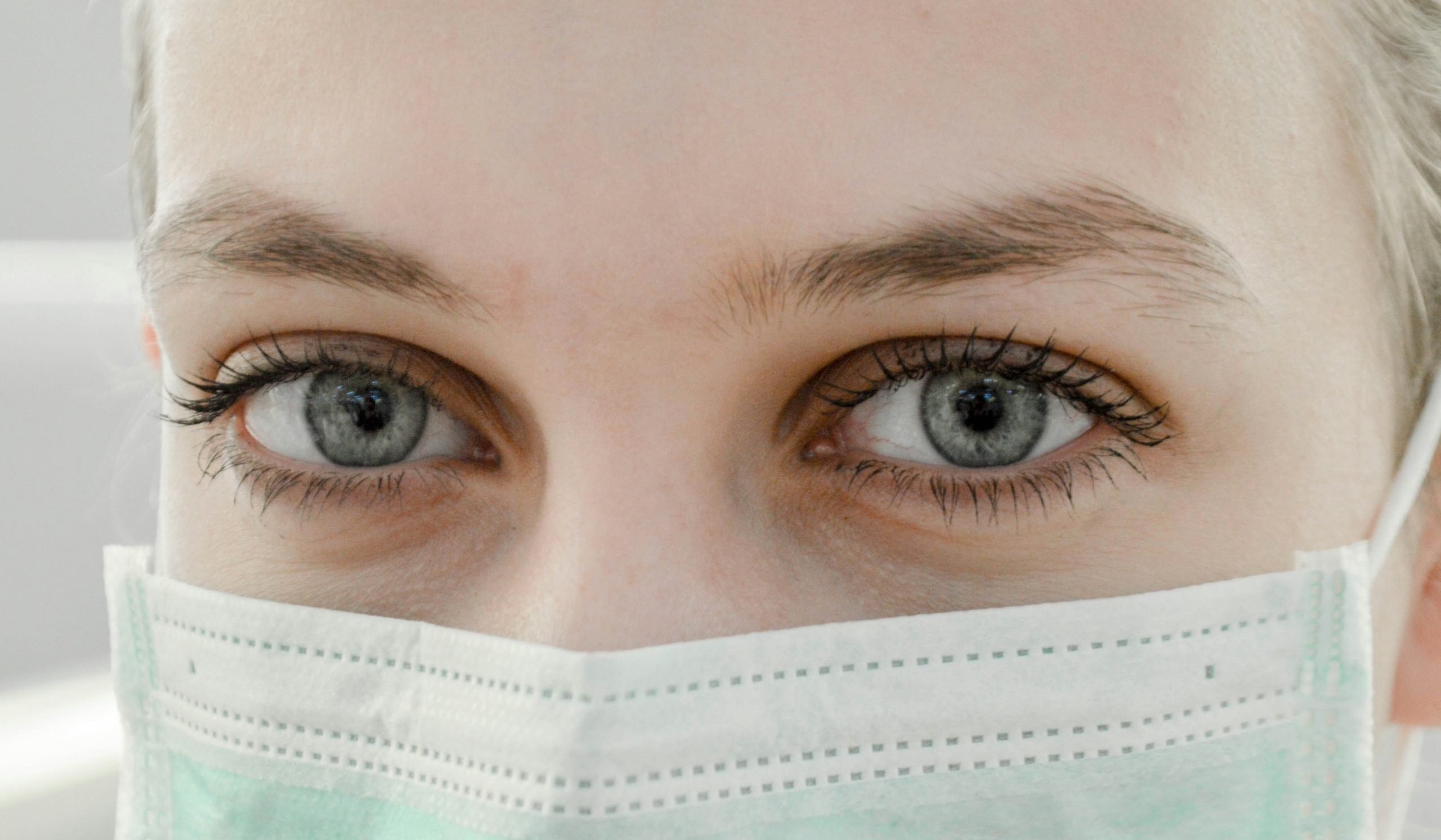A close-up of a woman's hazel eyes. She is wearing a protective mask, as one might do when ina doctor's office for women's hormone disorders.