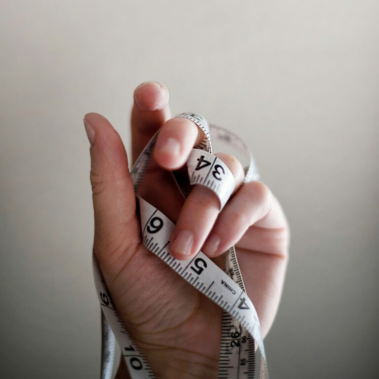 A hand holding a measuring tape.